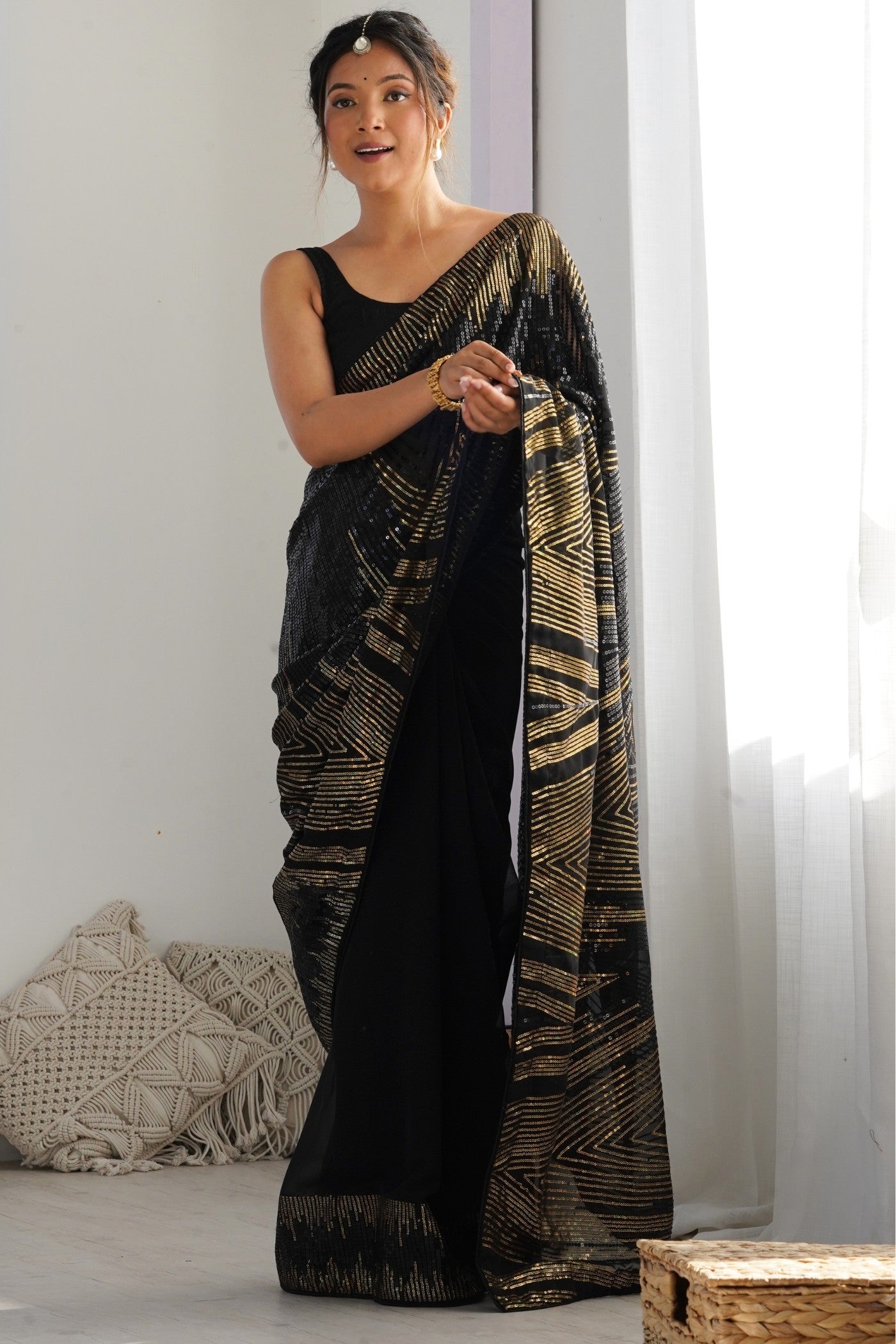 Model wearing a pitch black sequinned georgette partywear saree, the light fabric that suits a butterfly pallu drape